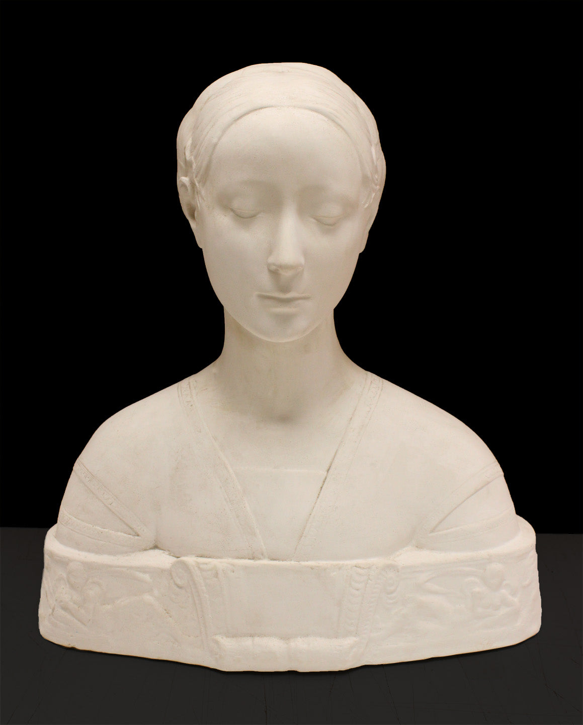 photo of white plaster cast sculpture of female bust cropped at shoulders with decorative base against black background