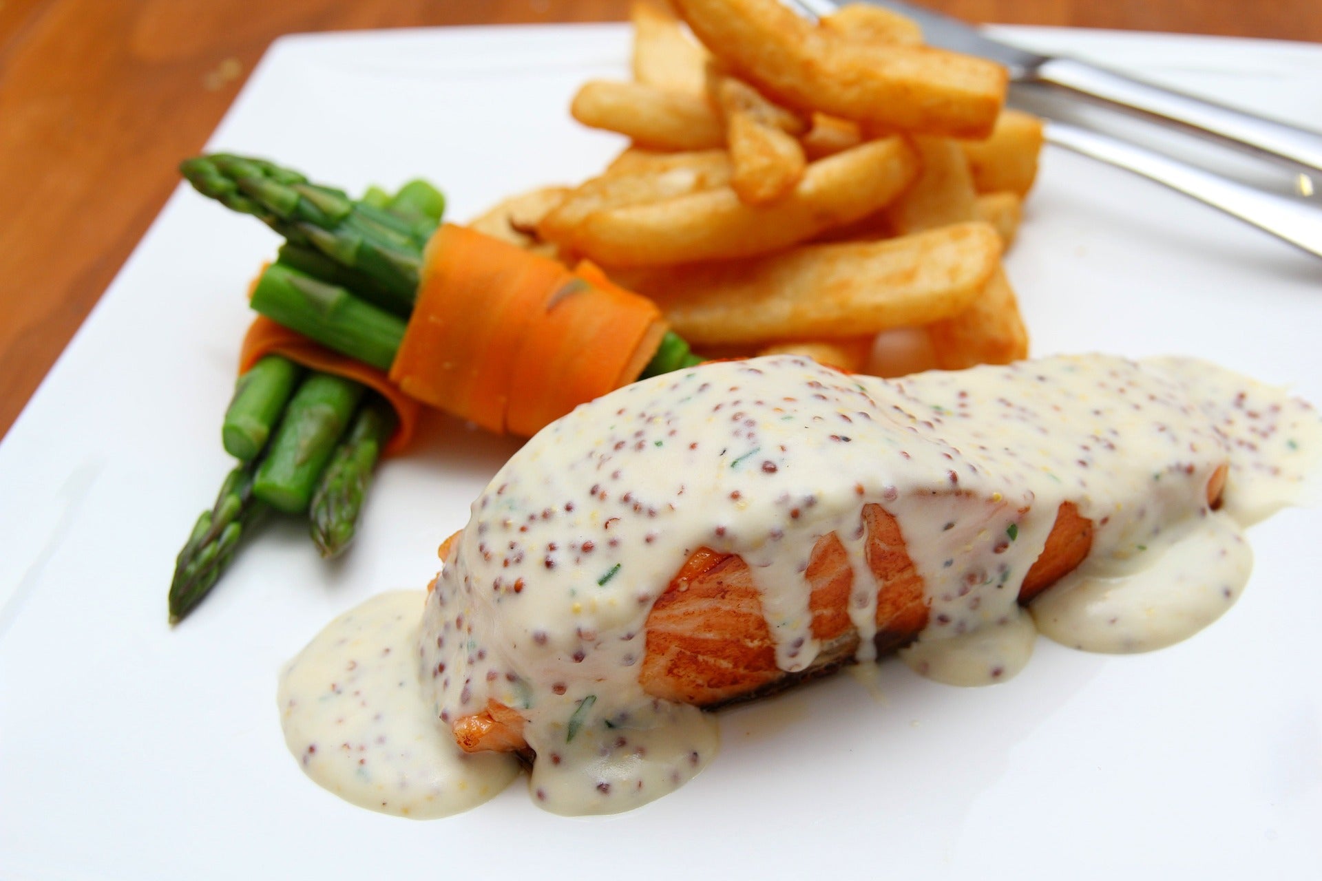 Photo of a meal with meat, vegetable, and fries on a plate and silverware