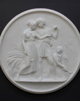 photo of white plaster cast relief sculpture of male and female figures walking through field of wheat and a female figure kneeling in the field cutting wheat against dark gray background