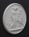 photo of white plaster cast relief sculpture of male and female figures walking through field of wheat and a female figure kneeling in the field cutting wheat against dark gray background