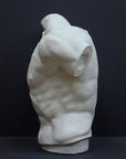 photo of white plaster cast sculpture of male torso, namely Laocoon, against gray background