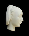 photo of white plaster cast sculpture mask of female with part-back hairdo against gray background