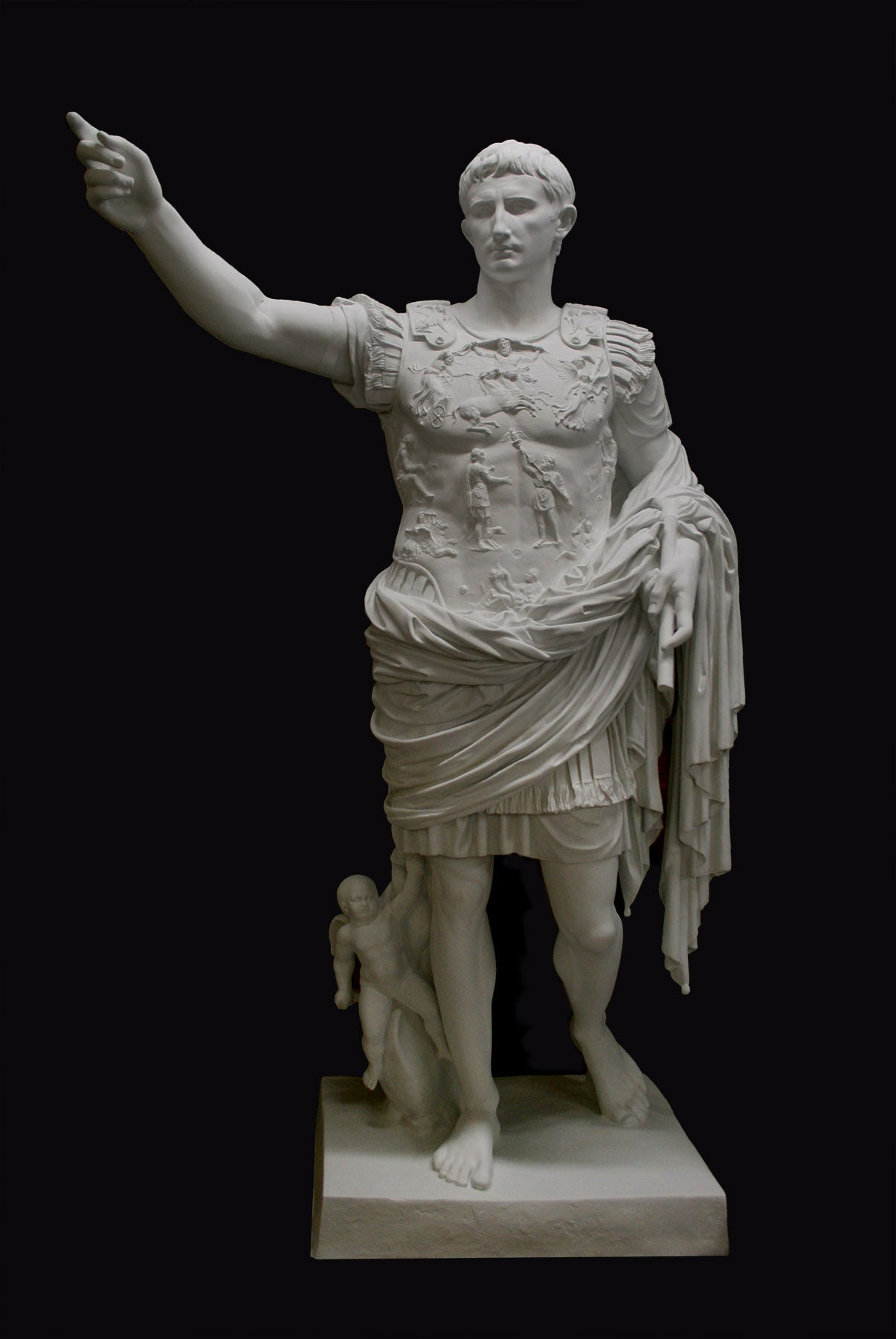 photo of white plaster cast sculpture of a man with armor and robes standing in contrapposto with his right arm raised, namely Augustus Caesar, against a black background