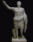 photo of white plaster cast sculpture of a man with armor and robes standing in contrapposto with his right arm raised, namely Augustus Caesar, against a black background