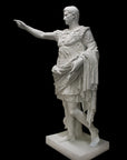 photo of white plaster cast sculpture of a man with armor and robes standing in contrapposto with his right arm raised, namely Augustus Caesar, against a black background