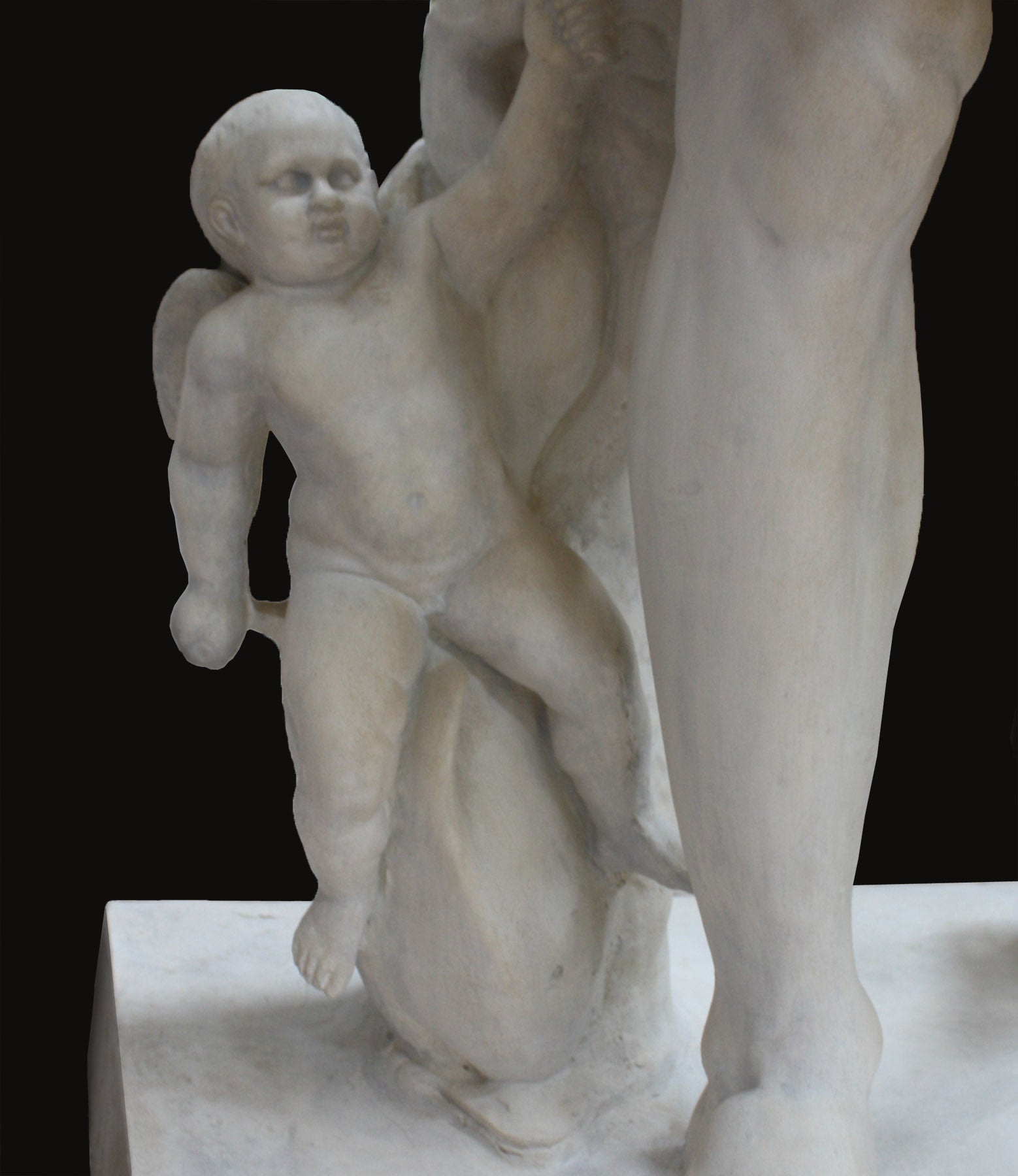 detail photo of Cupid on a dolphin from white plaster cast sculpture of a man with armor and robes standing in contrapposto with his right arm raised, namely Augustus Caesar, against a black background