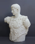 photo of white plaster cast sculpture of a man's torso with armor and robes with his right arm raised, namely Augustus Caesar, against a gray background