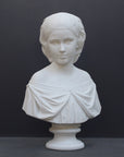 photo of white plaster cast bust sculpture of young woman with headband piece and in dress that falls off shoulders against a gray background