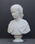 photo of white plaster cast bust sculpture of young woman with headband piece and in dress that falls off shoulders against a gray background