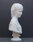 photo of white plaster cast bust sculpture of young woman with headband piece and in dress that falls off shoulders against a gray background