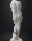 photo of white plaster cast sculpture of nude female figure hugging herself against gray background