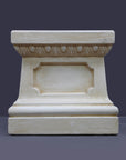 photo of off-white plaster cast reproduction of short, rectangular pedestal taken straight on and against a gray background