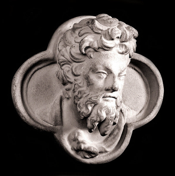 black and white photo of plaster cast sculpture of man's head in ornamental shape against black background