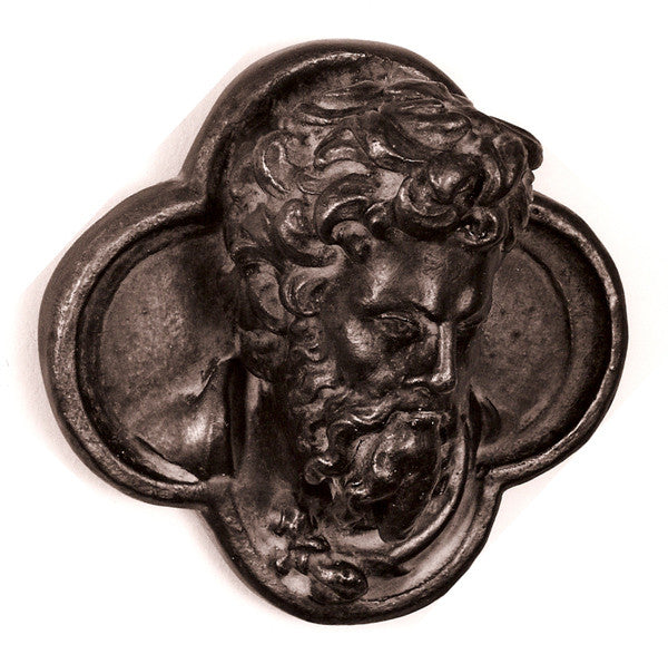 black and white photo of bronze-colored plaster cast sculpture of man's head in ornamental shape against white background