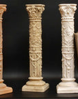 photo of three plaster casts of ornamental candlesticks in terra cotta, tan color, and ivory color and two books propped up against one with black background