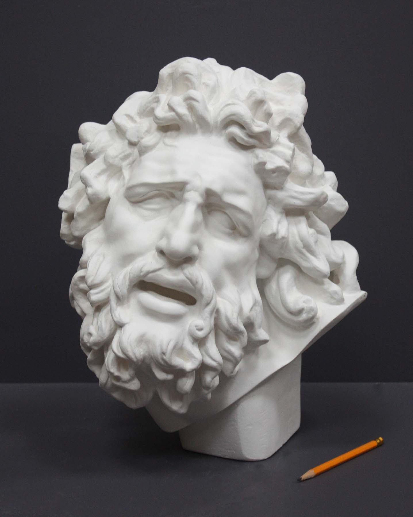 photo with gray background of plaster cast sculpture of male head with curly hair and beard, namely Laocoon, and yellow pencil