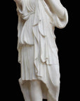 photo with black background of plaster cast of female figure, namely the goddess Diana, with robes about to clasp two pieces together at proper right shoulder