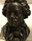 photo of bronze-colored plaster cast sculpture bust of man, namely Beethoven, with neckerchief on light-colored background