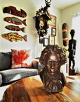 photo of bronze-colored plaster cast sculpture bust of man, namely Beethoven, with neckerchief on wooden table in room with various collectibles