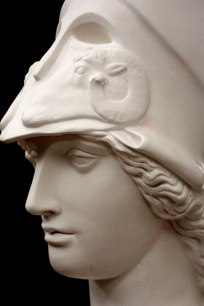 photo of plaster cast sculpture bust of female head, namely the goddess Athena, with a helmet on a black background