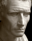 closeup photo with black background of plaster cast bust sculpture of a man, namely Antiochus III, with headband and clothing on the square bust