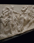 photo of a plaster cast sculpture relief of a woman, namely the goddess Aurora, flying and leading a chariot with a man pulled by horses towards the right while a cherub and other women fill the scene, on a black background