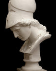 photo of plaster cast sculpture bust of female head, namely the goddess Minerva, with a helmet and looking down and placed on a pedestal with black background