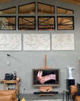 photo of row of three white plaster cast relief sculptures of men on horseback from Parthenon on gray wall under large windows and high ceiling with plaster cast statue of Victory of Samothrace and swan photo below