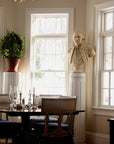 Photo of off-white plaster cast bust sculpture of male in Revolutionary garb, namely George Washington, on white pedestal in front of windows in a dining room