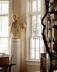 Photo of off-white plaster cast bust sculpture of male in Revolutionary garb, namely George Washington, on white pedestal in front of windows in a dining room