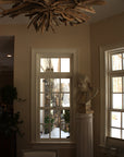 Photo of male bust sculpture on tall pedestal in between two windows in a dining room