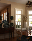 Photo of male bust sculpture on tall pedestal in between two windows in a dining room