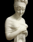 photo with black background of plaster cast sculpture bust of Madame Recamier with high up-do and ribbon over forehead and hands crossed over chest covered in cloth