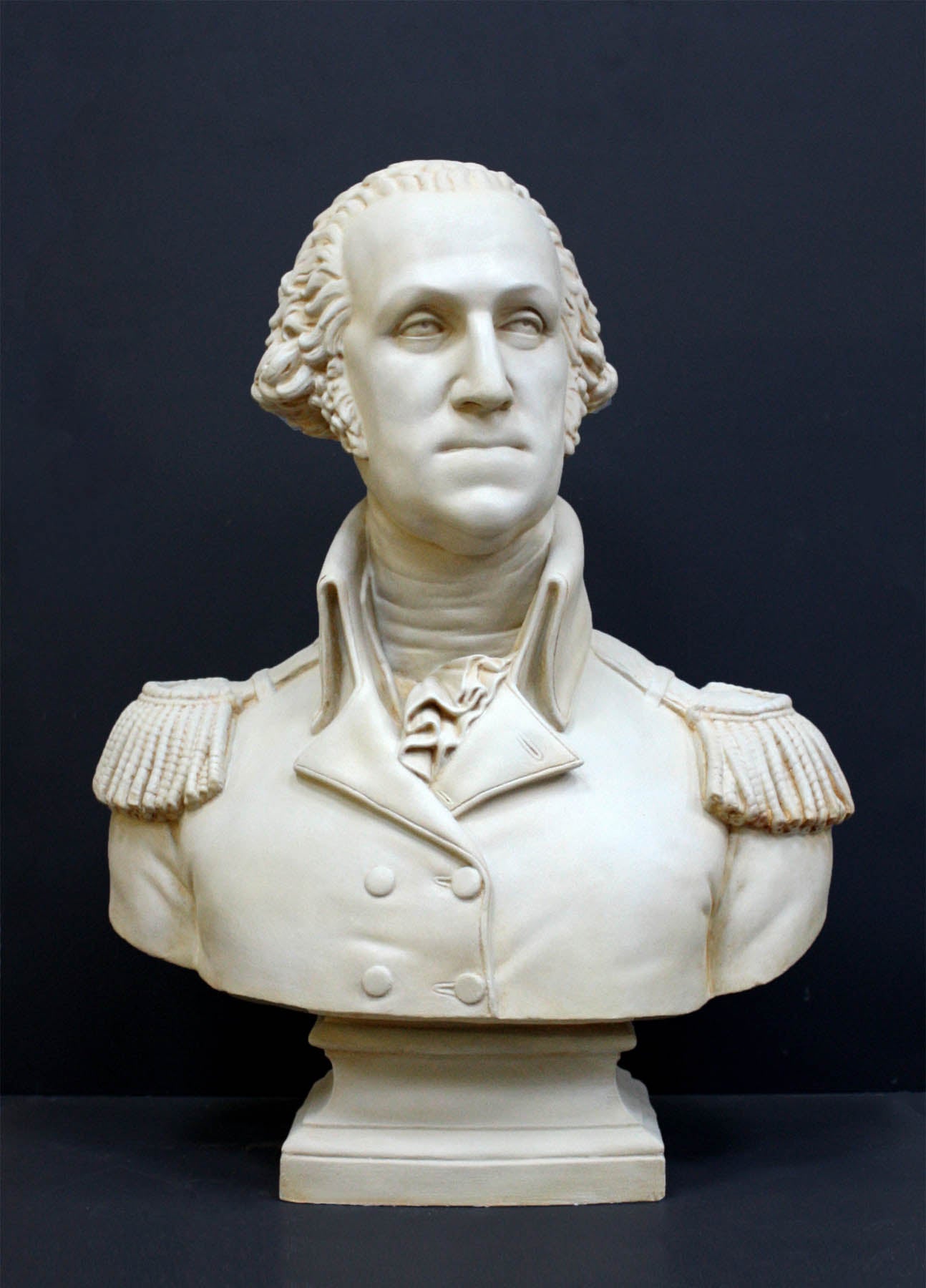 photo of plaster cast sculpture bust of George Washington in uniform on dark gray background