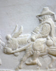 closeup photo of plaster cast relief sculpture of man riding donkey in profile