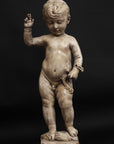 photo of plaster cast sculpture of nude male child, namely Christ, with raised right arm on a black background