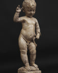 photo of plaster cast sculpture of nude male child, namely Christ, with raised right arm on a black background