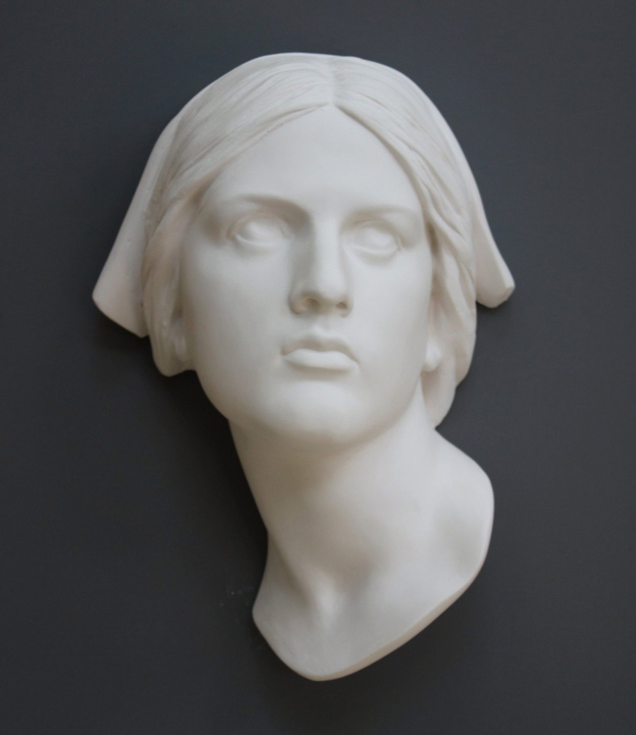 photo with gray background of plaster cast sculpture of Joan of Arc's face and portion of kerchief on head