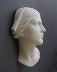 photo with gray background of plaster cast sculpture of Joan of Arc's face and portion of kerchief on head