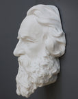 photo of plaster cast of man's head, namely Longfellow, with long hair and curly beard on gray background