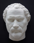 photo of white plaster cast of sculpture of face of Demosthenes with curly hair and beard on black background