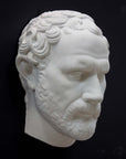 photo of white plaster cast of sculpture of face of Demosthenes with curly hair and beard on black background