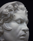 photo of plaster cast of sculpture of face of Sleeping Faun with two flowers in curly hair on dark gray background