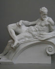 photo of plaster cast of reclining male nude with a gray background