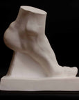 Photo of plaster cast sculpture of foot on a black background