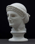 photo of plaster cast sculpture of archaic Greek male head with hair in fillet and ringlets on dark gray background