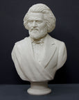 photo of white plaster cast sculpture of bust of Frederick Douglass with beard and in suit coat with toga over one shoulder on dark gray background