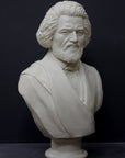 photo of white plaster cast sculpture of bust of Frederick Douglass with beard and in suit coat with toga over one shoulder on dark gray background