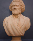 photo of terracotta-colored plaster cast sculpture of bust of Frederick Douglass with beard and in suit coat with toga over one shoulder on dark gray background