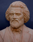 photo detail of terracotta-colored plaster cast sculpture of bust of Frederick Douglass with beard and in suit coat with toga over one shoulder on dark gray background